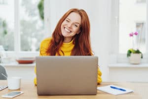 Young happy red-haired woman using laptop