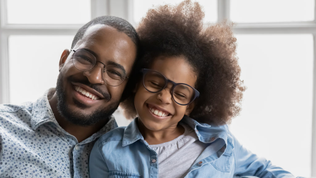 Close up portrait of cheerful father and daughter, both are wearing glasses.