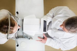 A birds eye view of an eye doctor checking the vision of a woman in an optometry office.